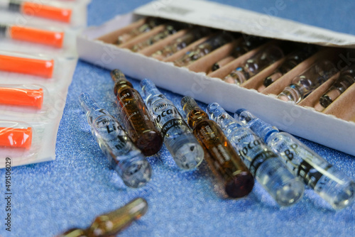 Medical ampoules full of medicine  their box and insulinic syringe on a blue background