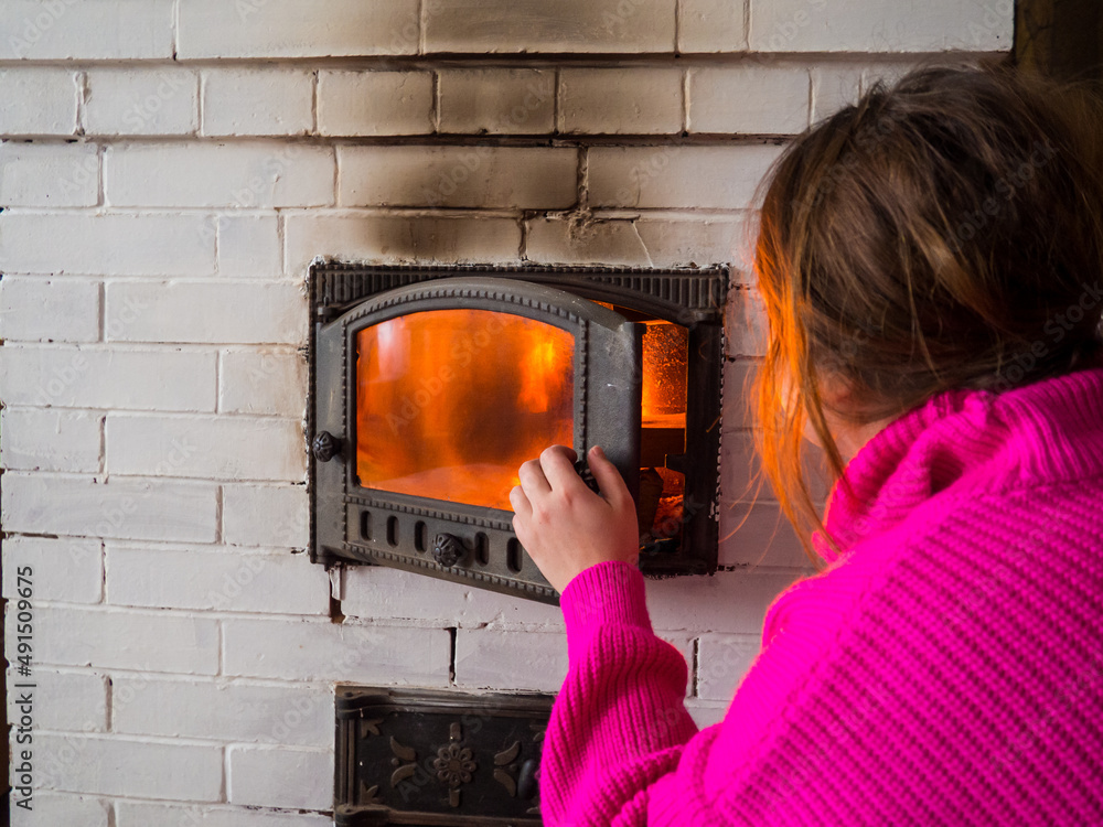 girl throws firewood into the fire in the stove. Furnace firebox in the