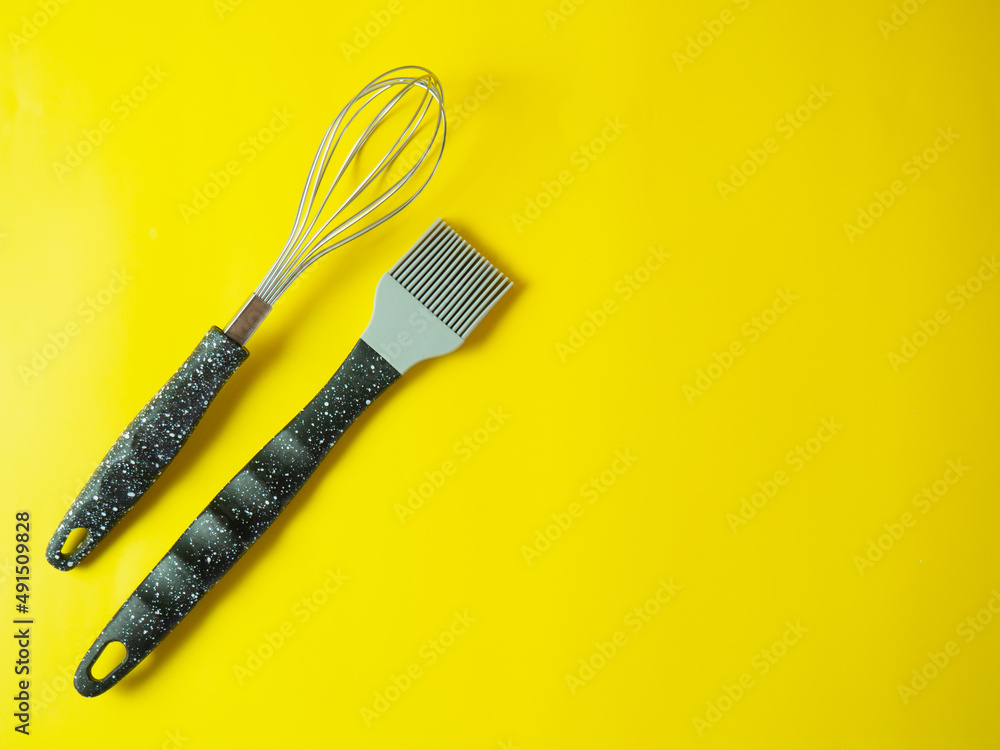 whisk and oil brush on yellow background.cooking concept whisk and oil brush on yellow background.cooking concept