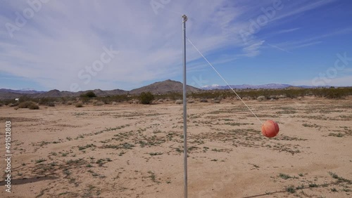 This wide shot, surreal video shows an old, remote tether ball wrapping around a pole in the desert. photo