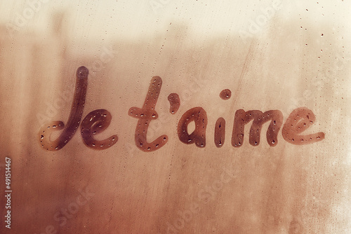 Hand drawn French words Je taime I love you in english on foggy glass of window photo