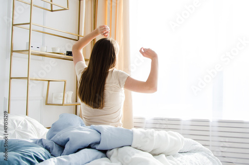the girl woke up in the morning and shadowed her hands up. concept to meet the dawn on the bed