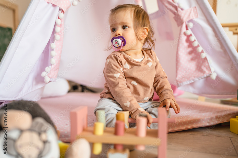 One baby small caucasian infant girl playing on the floor at home copy space One baby small caucasian infant girl playing on the floor at home copy space