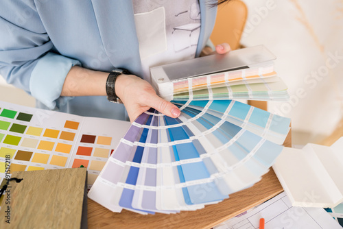 Close-up of architect woman choosing samples of wall paint. Interior designer looking at color swatch for creating project. House renovation, architecture and interior design concept.
