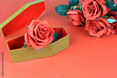 Artificial red rose in a small coffin. funeral flowers concept.