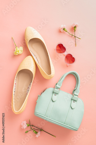 Fashion spring accessories for woman. Mint handbag and yellow ballet flats shoes on pastel pink.