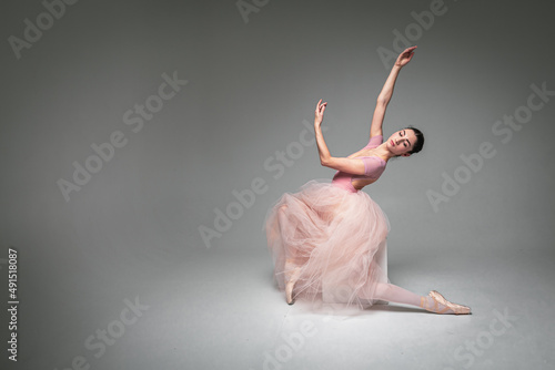 Fototapeta Naklejka Na Ścianę i Meble -  young pretty, fragile, beautiful ballerina dancing in a long pale pink dress with a tulle on a uniform background, hand movements, restrained tone. Ballet, dance, dancer. Place for inscription