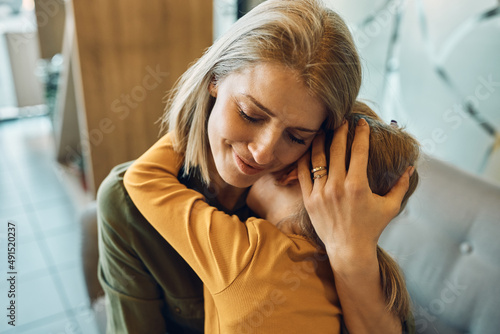 Loving mother embraces her sad little girl and consoling her at home. photo