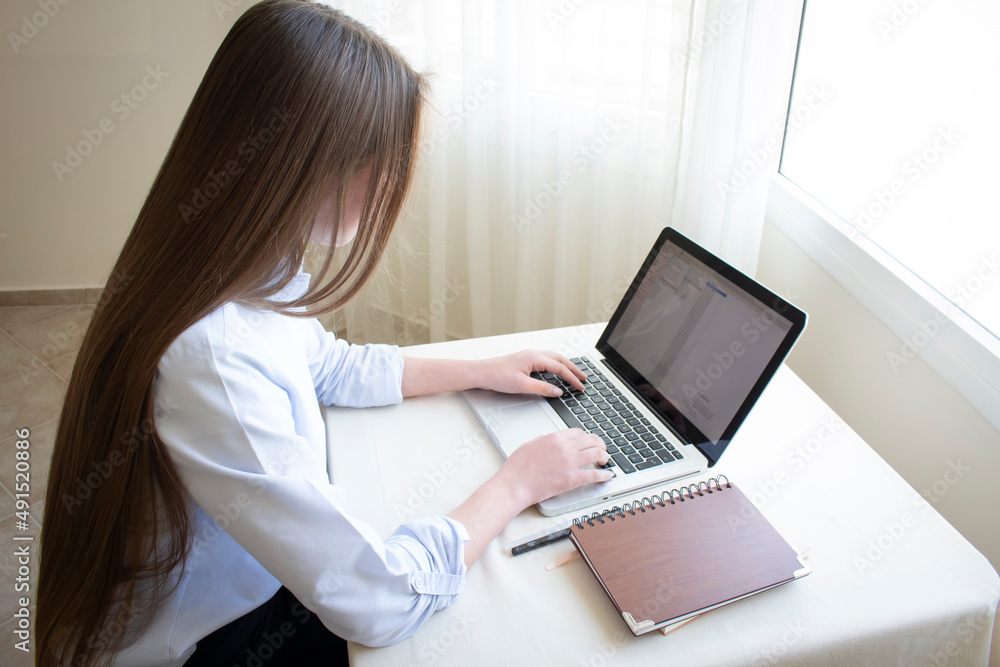 beautiful girl with long hair is sitting at a computer to study or work beautiful girl with long hair is sitting at a computer to study or work