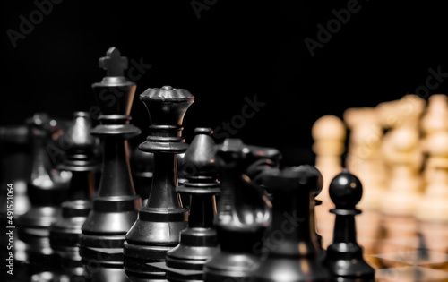 Close up of Chess pieces on a reflective mirror board surface with black background