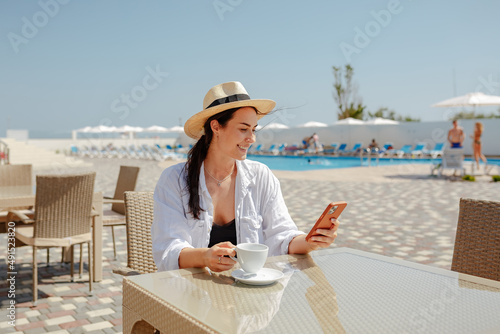 Smiling girl sitting by the pool looking at the phone