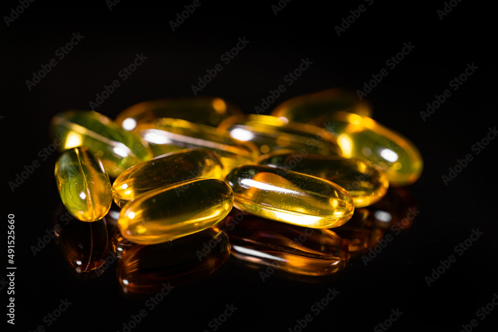 Close up of Omega 3 gel capsule on a reflective black background Close up of Omega 3 gel capsule on a reflective black background