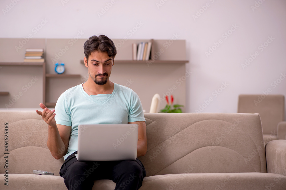 Young man sitting on the sofa with computer at home Young man sitting on the sofa with computer at home