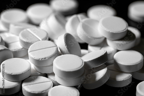 Close up of white painkiller tablet on a reflective black background
