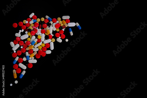 many colored tablets, pills, capsules with medicine on a black background, the concept of maintaining health, supporting the body with medicines, vitamins, dietary supplements, top view