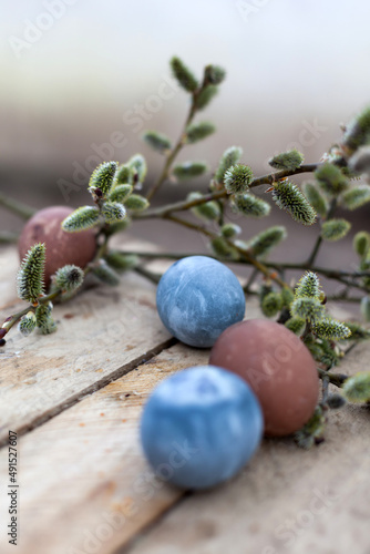 Colored Easter eggs and willow on  wooden background .