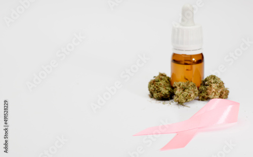 pink ribbon, set of marijuana buds, with dispenser bottle, white background.