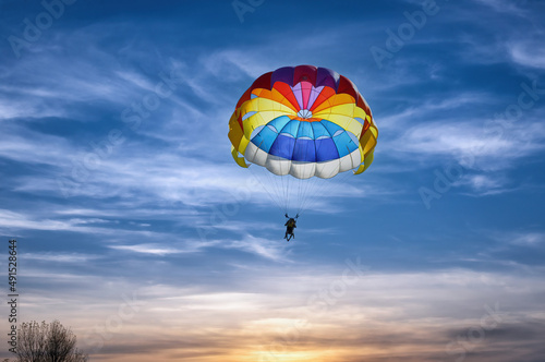 Gliding with a parachute on the background of bright sunset.