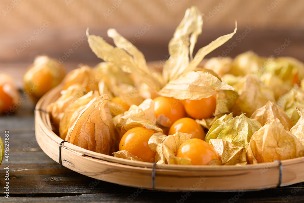 Cape gooseberry or goldenberry (Physalis peruviana) in bamboo basket on wooden, Healthy tropical fruit Cape gooseberry or goldenberry (Physalis peruviana) in bamboo basket on wooden, Healthy tropical fruit