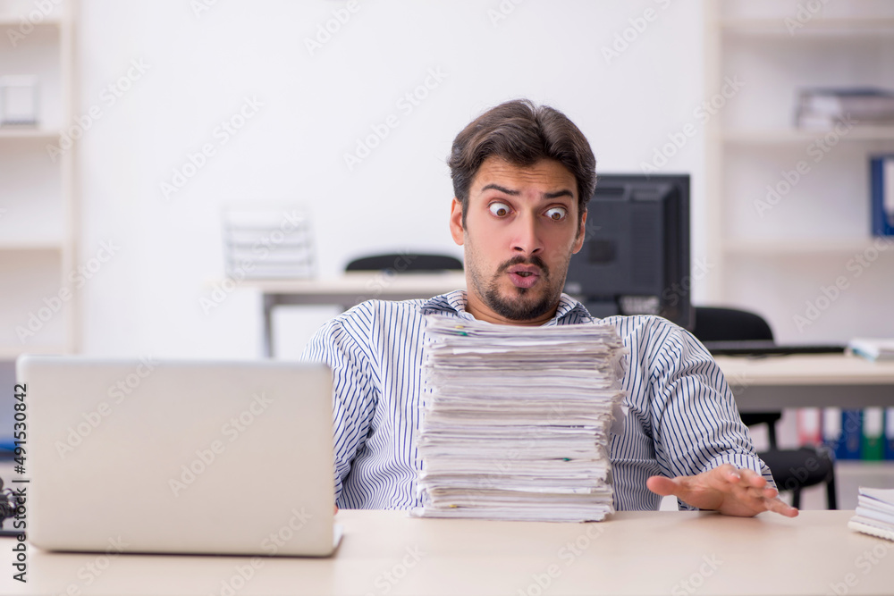 Obraz premium Young male employee and too much work in the office
