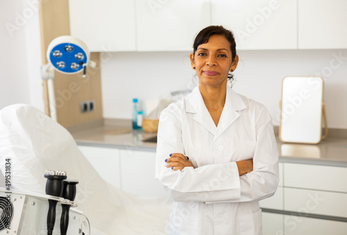 Portrait of Latin woman beauty doctor standing in office. photo
