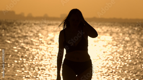 Silhouette shot of a beautiful woman on sunset shot against the golden ocean water
