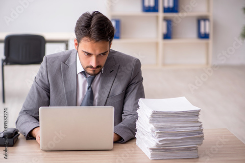 Young male employee and too much work in the office