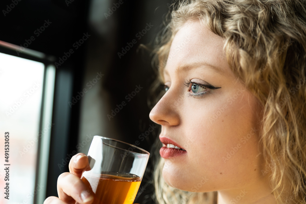 Window portrait of a 21 year old white blonde woman with curling hair holding a glass of champaign Window portrait of a 21 year old white blonde woman with curling hair holding a glass of champaign