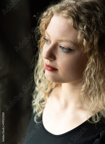 Window portrait of a 21 year old white blonde woman with curling hair