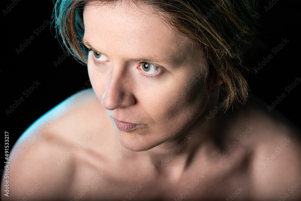 Low key studio portrait of a 35 year old white woman with naked shoulders and chest Low key studio portrait of a 35 year old white woman with naked shoulders and chest