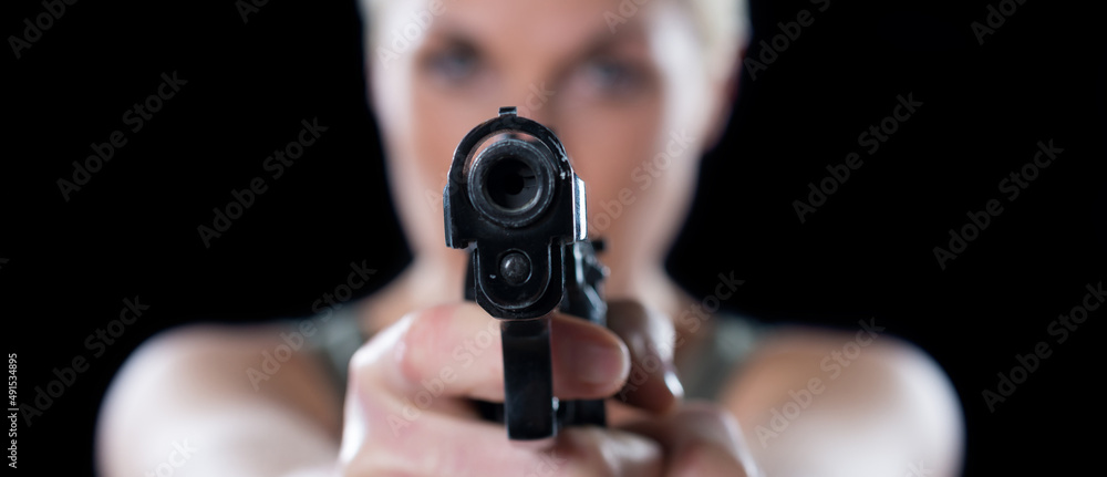 Young woman shooting with the gun isolated on black background. Young woman shooting with the gun isolated on black background.