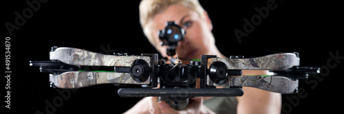 Photo Young woman shooting with crossbow isolated on black background.