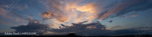 Landscape with bloody sunset. Panorama. Tragic gloomy sky. The last flashes of the sun on the storm clouds.