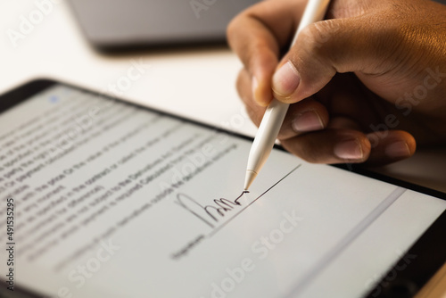 Close up businessman hand electronic Signature on Tablet by Stylus. Write business agreement of contract. Man signing contract on tablet. Business and technology concept.