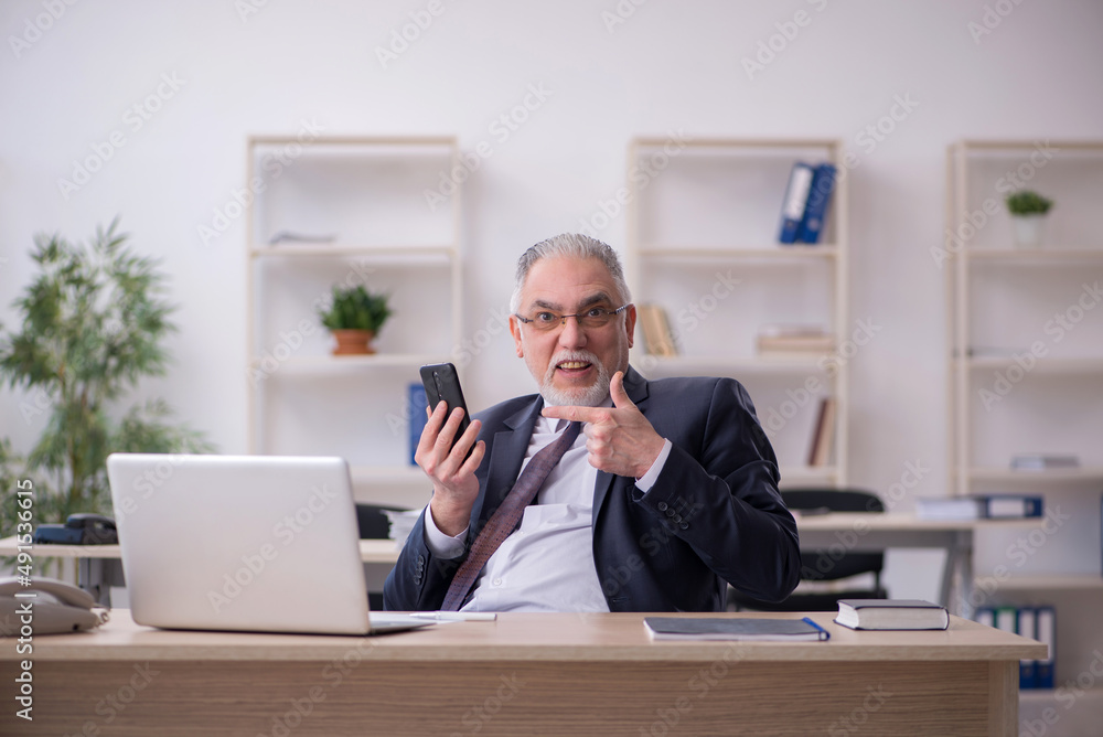 Old male employee sitting at workplace Old male employee sitting at workplace
