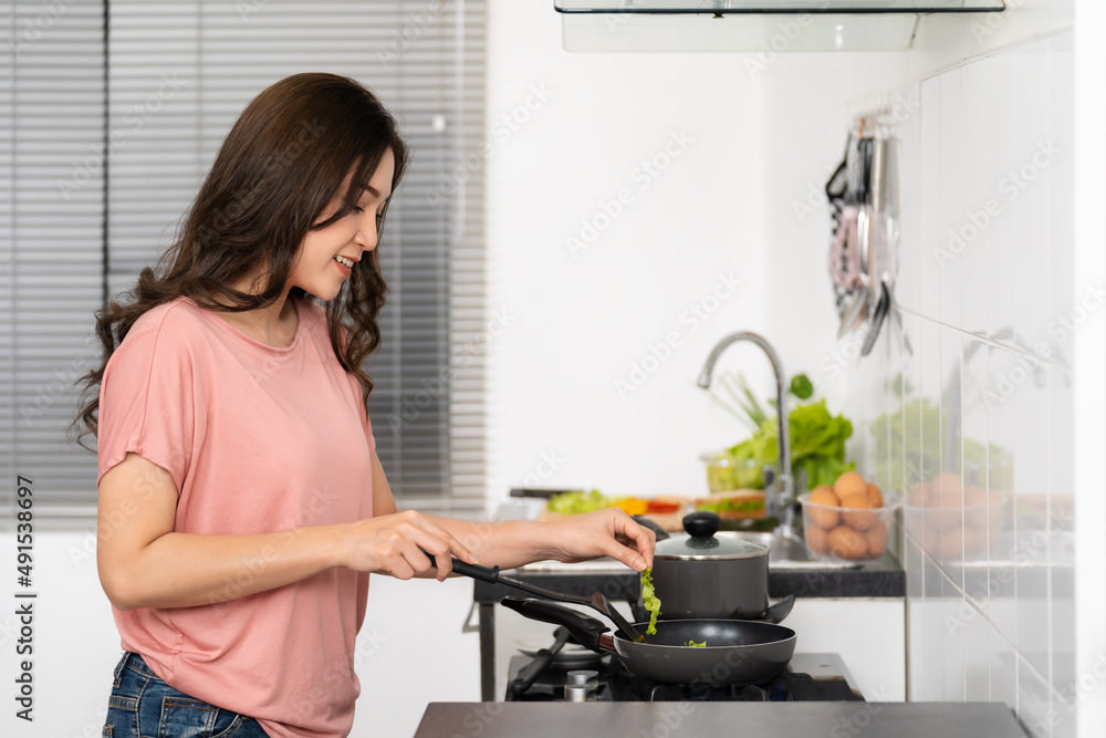happy woman cooking and preparing food in the kitchen at home happy woman cooking and preparing food in the kitchen at home