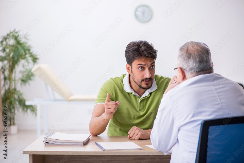 Young man visiting old male doctor