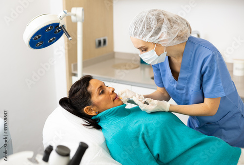 Mexican woman getting procedure of injection contouring and lip augmentation in cosmetology clinic
