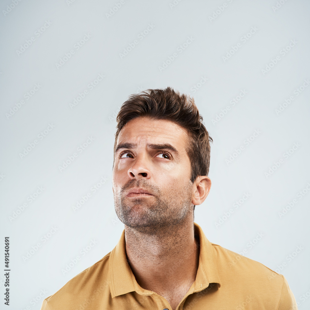 Fototapeta premium My head is in a world of wonder. Studio shot of a young man with a confused facial expression while standing against a grey background.