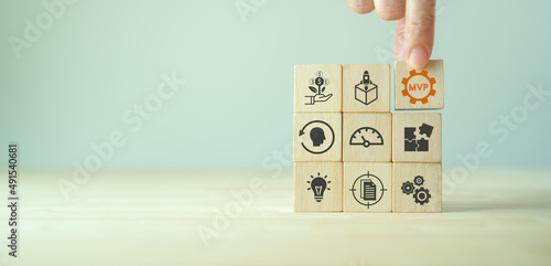 MVP, minimum viable product concept for lean startup. Life cycle of product development. Analysis and market validation. Hand puts wooden cubes with abbreviation MVP and learn, build, measure icons.
