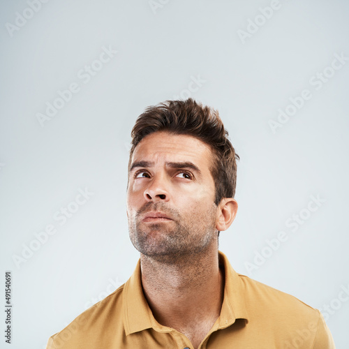 My head is in a world of wonder. Studio shot of a young man with a confused facial expression while standing against a grey background.