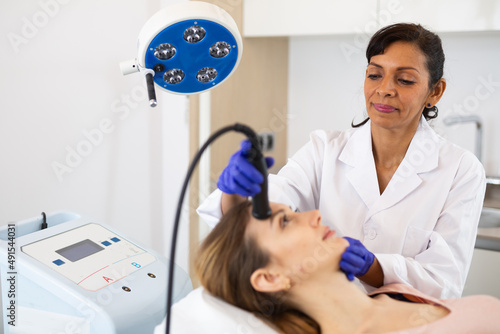 Young adult woman receiving needle-free mesotherapy procedure for face for wrinkle and fine line improvements at clinic