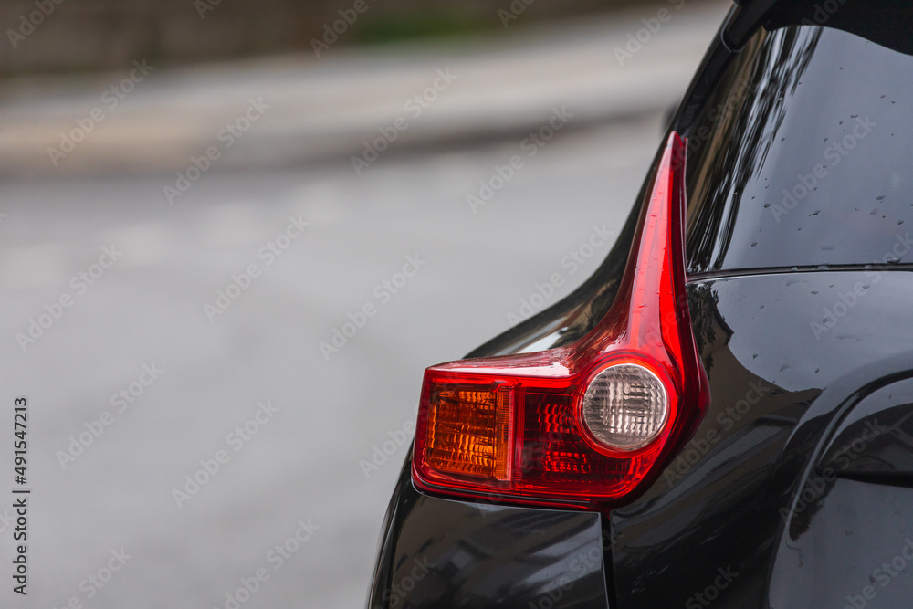 Close up  of modern black car xenon lamp taillight, bumper, rear trunk lid. Exterior of a modern car.