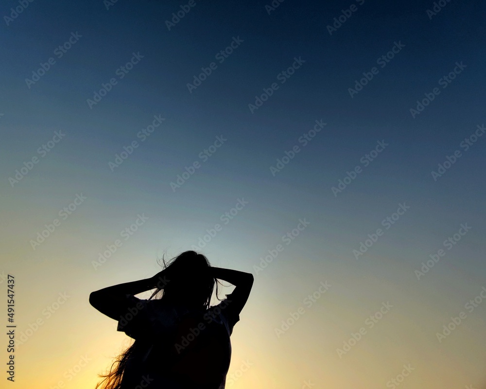 silhouette of a woman in front of blue and yellow sky with space to write your text 