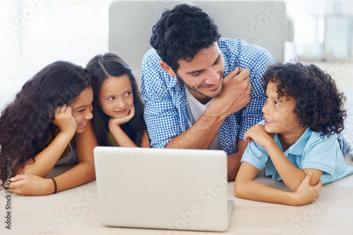 Exploring online together. Shot of a smiling family lying on the floor and surfing the internet.