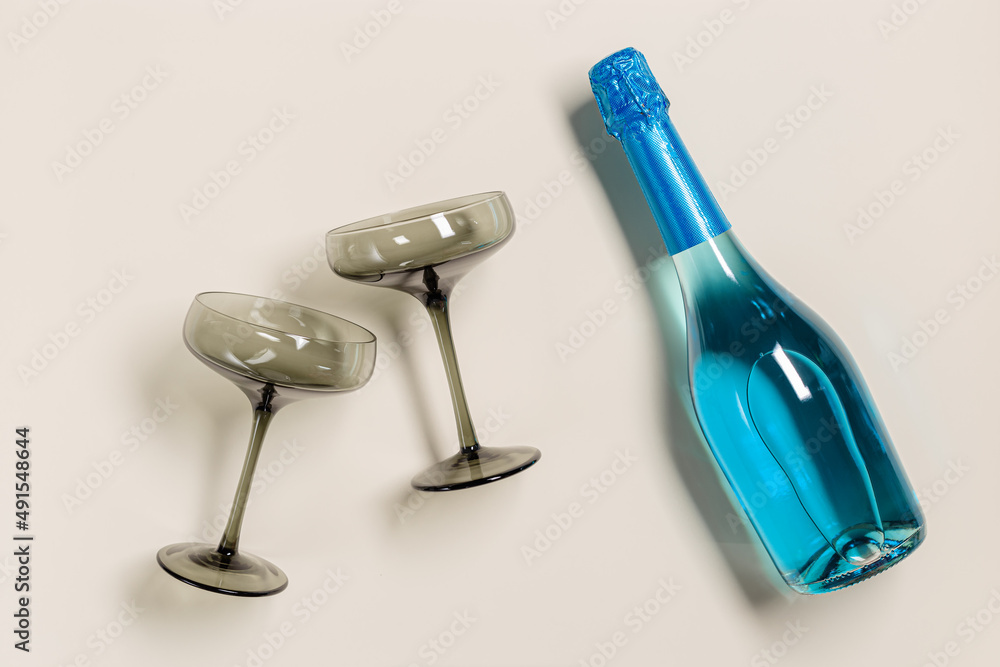 Champagne glasses tinted grey glass, Blue Champagne or blue sparkling wine bottle. Light Festive drink concept, glare and sunlight. Modern wine colored glasses. Creative flat lay Champagne glasses tinted grey glass, Blue Champagne or blue sparkling wine bottle. Light Festive drink concept, glare and sunlight. Modern wine colored glasses. Creative flat lay