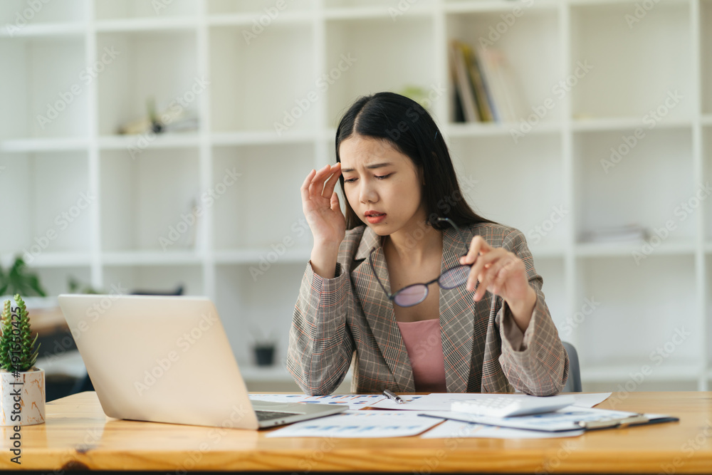 Young attractive woman at modern office desk, working on laptop, massaging temples to forget about constant headaches, noisy loud office giving a migraine, relieving stress, chronic pain, help soothe Young attractive woman at modern office desk, working on laptop, massaging temples to forget about constant headaches, noisy loud office giving a migraine, relieving stress, chronic pain, help soothe