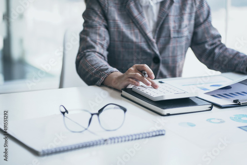 Close up Business woman using calculator with business chart financial graph at desk in office.