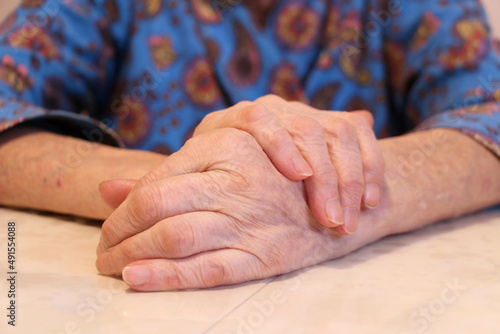 Symptoms of arthritis disease. Close-up of a tremor (shaking) of the hands of a middle-aged female patient on a white table. The concept of mental health and neurological disorders.