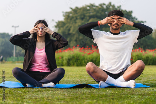 Young couple doing yoga and meditating in the park early in the morning. Healthy lifestyle concept.